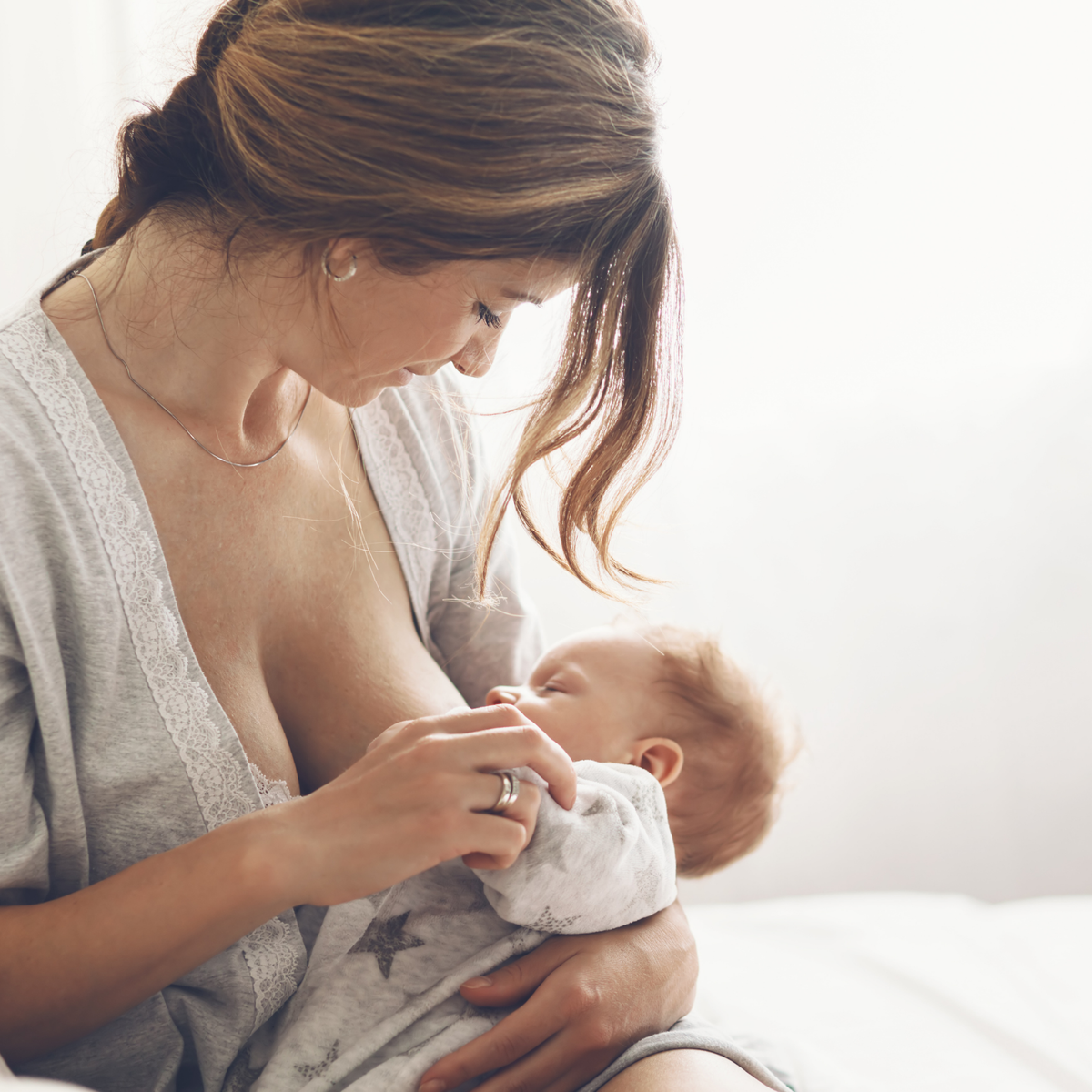 Jeune maman allaitant son nouveau-né à la maison pendant le post-partum